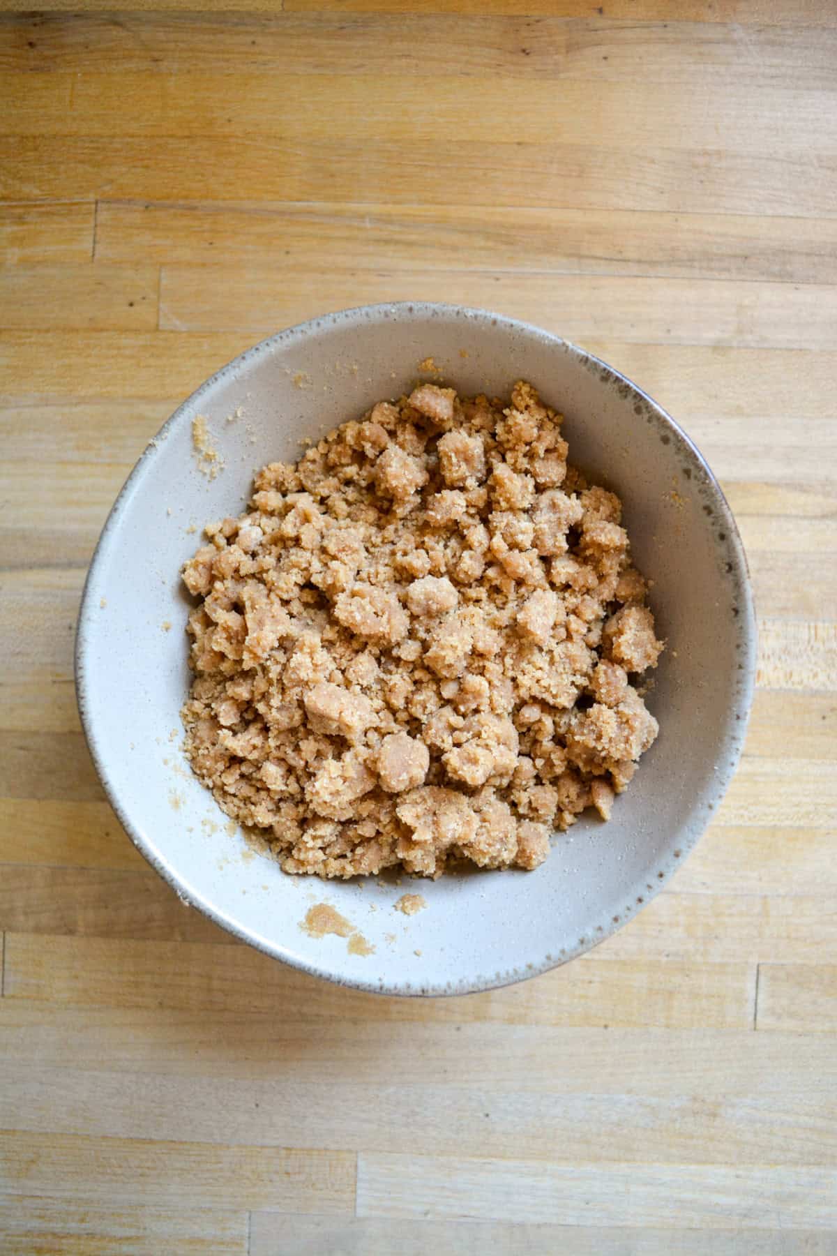 Coffee cake streusel topping in a bowl on a wooden surface.