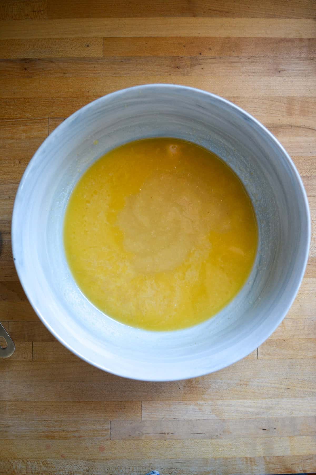 Wet ingredients for this recipe in a large bowl on a wooden surface.