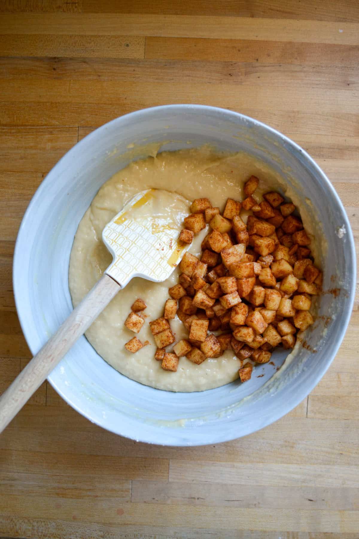 Coffee cake batter topped with cinnamon apples in a large bowl.