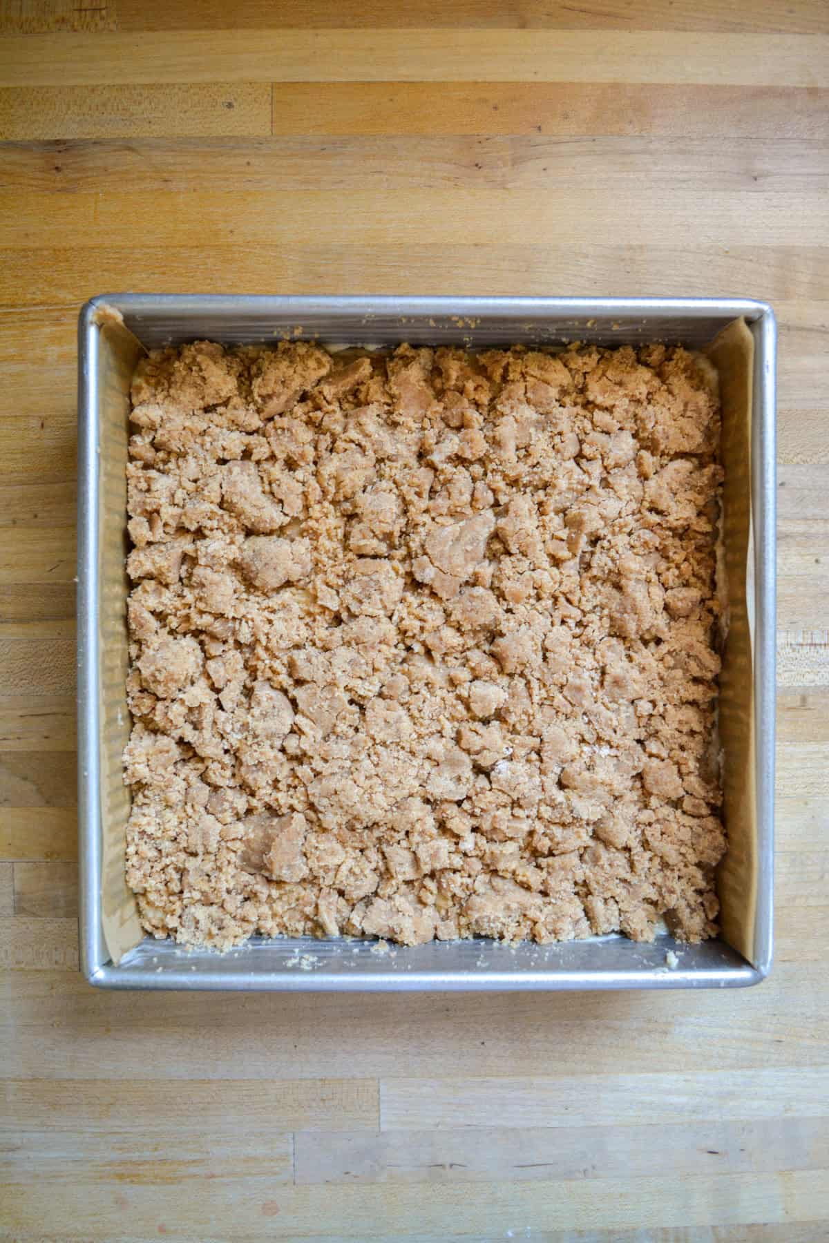 Crumb cake batter in a square baking pan topped with streusel.