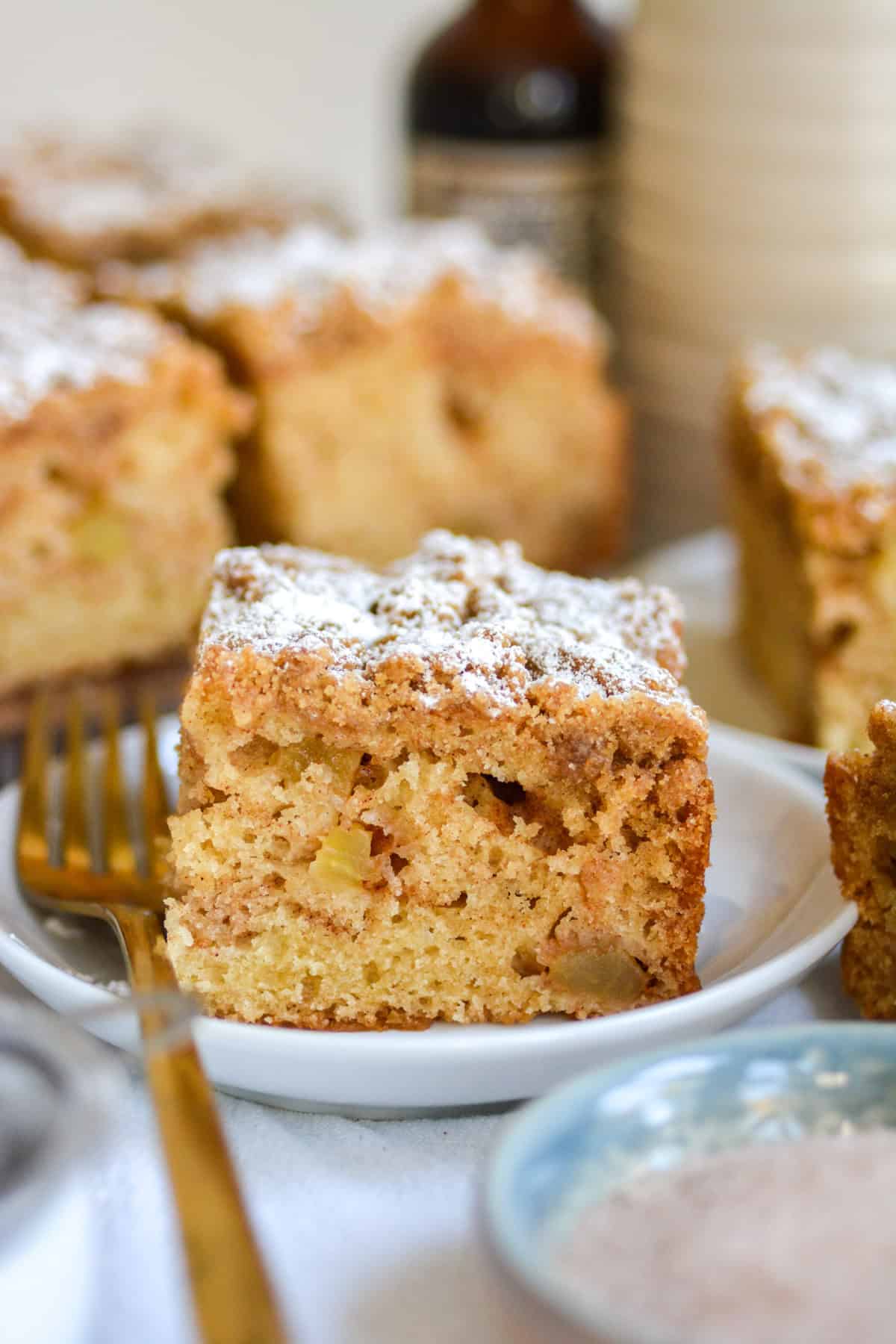 A slice of Vegan Apple Crumb Cake on a plate with a gold fork.