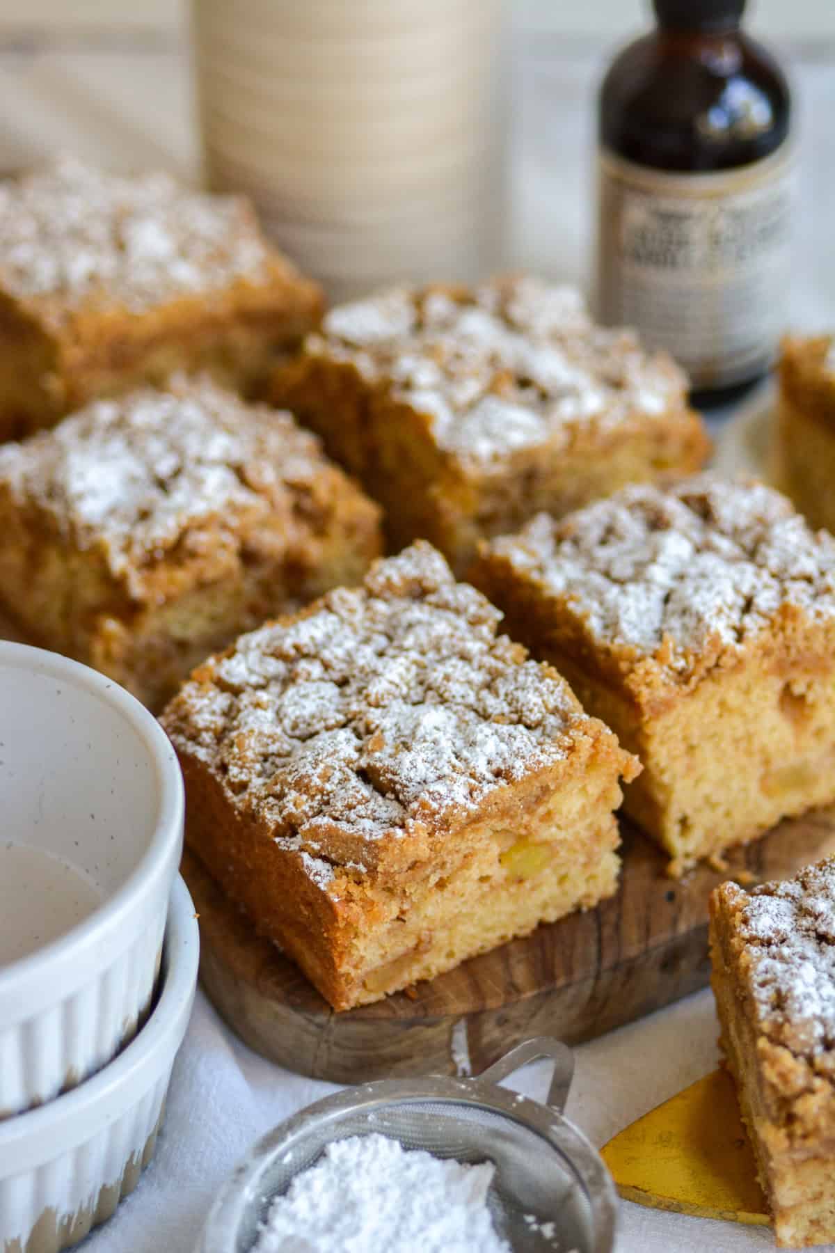 Vegan Apple Crumb Cake squares topped with powdered sugar on a small wooden cutting board.