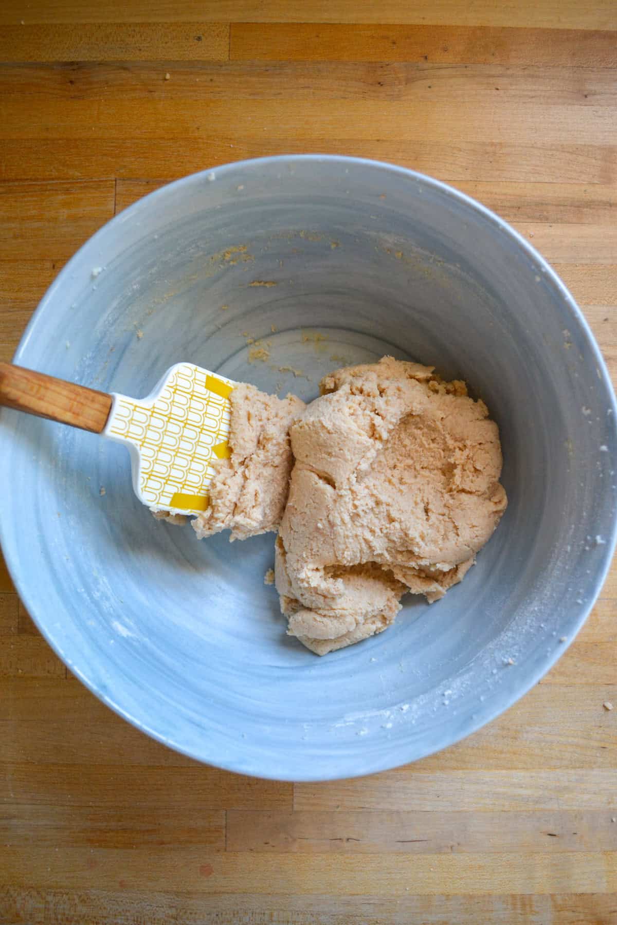 Vegan Snickerdoodle Cookie dough in a large mixing bowl with a spatula in it.
