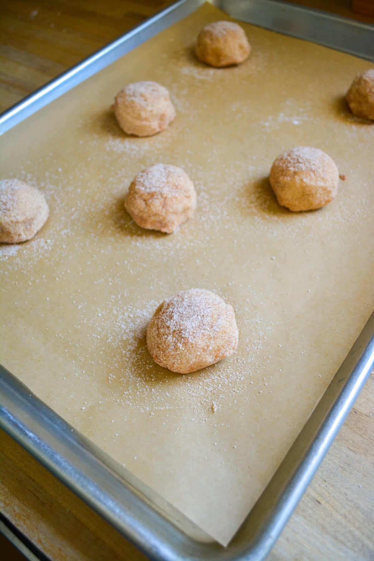 Cookie dough balls on a parchment-lined baking sheet ready to go into the oven.